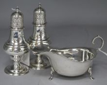 A pair of late Victorian silver pepperettes and a silver sauceboat.