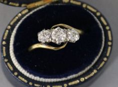 An 18ct gold and platinum, three stone diamond ring, size M.