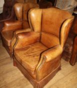 A pair of French 1940's brown leather armchairs