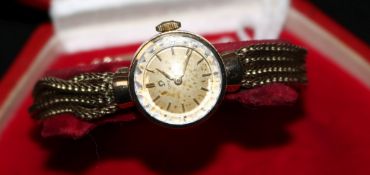 A lady's 9ct gold Omega manual wind wrist watch on an associated quadruple strand bracelet, with