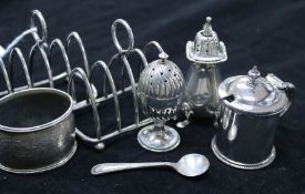 A group of small silver including two toastracks, a pepper pot, a napkin ring and two plated