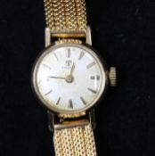 A lady's gold plated and steel Tissot manual wind wrist watch on a textured gold bracelet.