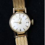 A lady's gold plated and steel Tissot manual wind wrist watch on a textured gold bracelet.