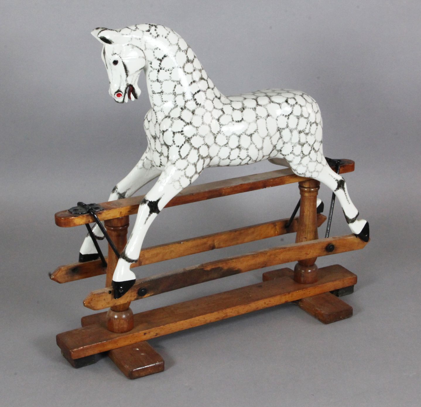 An Edwardian dapple painted wood rocking horse, with glass inset eyes, and trestle base, L.3ft H.2ft