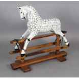 An Edwardian dapple painted wood rocking horse, with glass inset eyes, and trestle base, L.3ft H.2ft