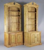 A near pair of classical style pine open bookcases, with broken arch pediments,