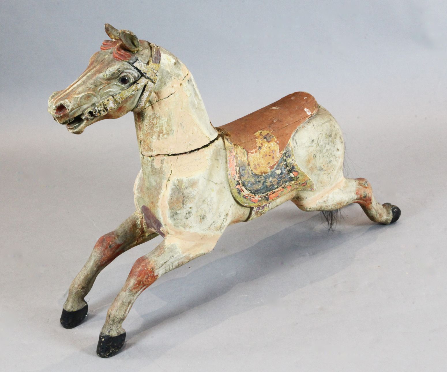 An early 20th century carved and painted wood carousel horse, with glass eyes, W.39in. H.27in.