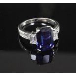 An attractive platinum, three stone sapphire and diamond ring with diamond set shoulders, with