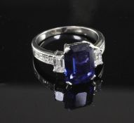 An attractive platinum, three stone sapphire and diamond ring with diamond set shoulders, with