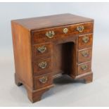 An early 18th century crossbanded kneehole desk, with eight drawers around a central recessed
