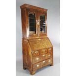 An early 18th century walnut bureau bookcase, with two glazed doors enclosing pigeonholes and