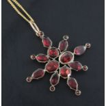 A Victorian gold and garnet set star pendant, with closed back setting, on a later fine link