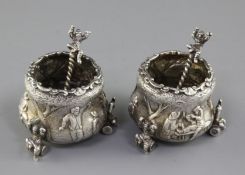 An ornate pair of Victorian silver tub shaped salts and spoons by F.B. Thomas & Co, embossed with