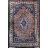 A Persian silk rug, with central foliate medallion in a field of scrolling foliage, on a pink