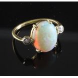 An 18ct gold, white opal and diamond ring, the central oval opal flanked by two round cut