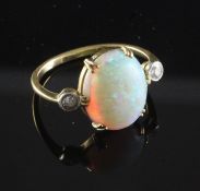 An 18ct gold, white opal and diamond ring, the central oval opal flanked by two round cut