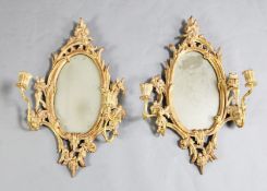 A pair of Chippendale carved giltwood girandoles with oval plates and flower sconces
