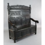A 17th century style inlaid oak monks bench, carved with armorials and inscribed 'de bon vouloir