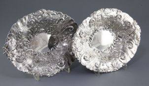 A matched pair of late Victorian silver oval dishes, embossed with scrolls and foliate decoration,