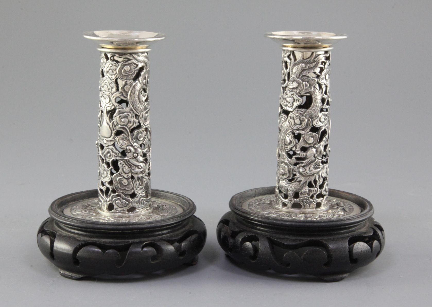 A pair of early 20th century Chinese Export repousse silver dwarf candlesticks, pierced and