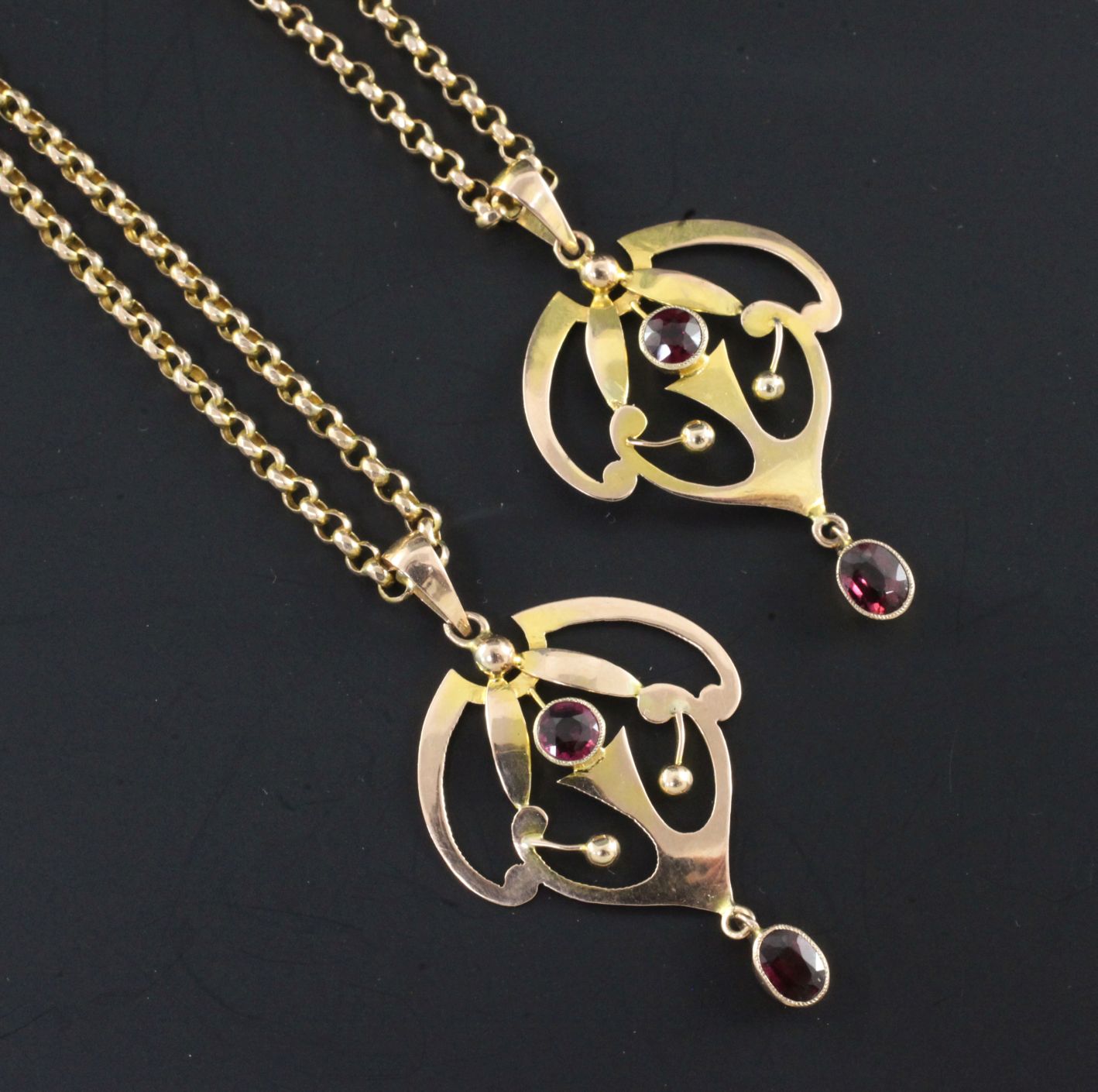 A pair of Edwardian Art Nouveau 9ct gold and garnet set drop pendants on 9ct gold chains, pendants