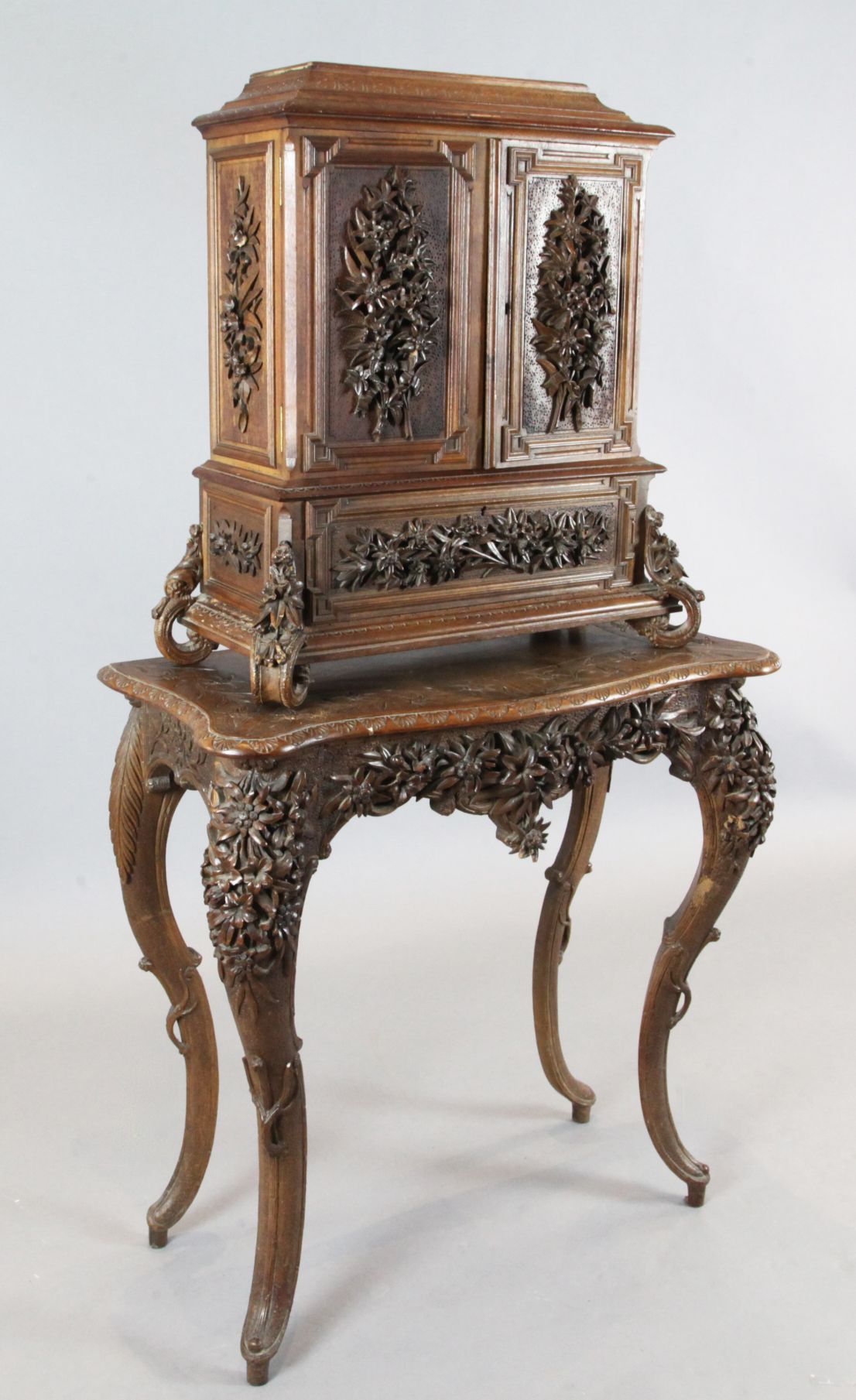 A late 19th century Black Forest relief carved wood cabinet on stand, decorated in relief throughout