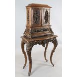 A late 19th century Black Forest relief carved wood cabinet on stand, decorated in relief throughout