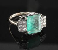 An Art Deco 18ct gold and platinum, emerald and diamond dress ring, the central emerald flanked by