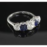 A mid 20th century platinum and graduated five stone sapphire and diamond half hoop ring, size M.