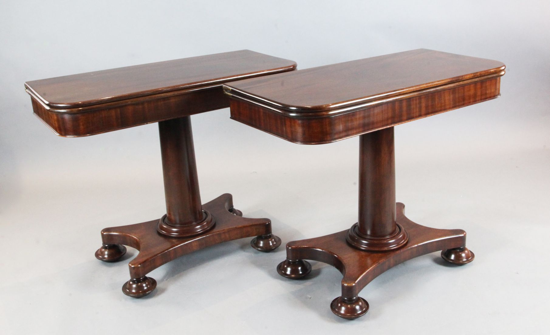 A pair of early Victorian mahogany tea tables, with folding D shaped tops, on turned stems and