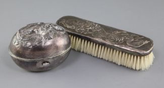 An early 20th century Japanese silver soap box and a clothes brush, both embossed with dragons,