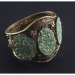 A Chinese silver gilt filigree bracelet inset with three carved jadeite oval foliate panels.
