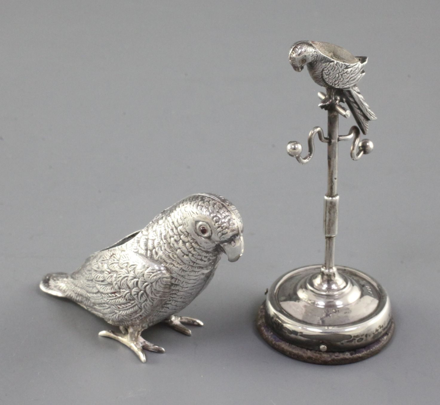 An Edwardian silver mounted combination pin cushion/ring tree modelled as a parrot on a perch,