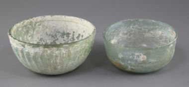 Two Roman pale green glass bowls, 2nd to 4th century AD, the larger bowl with ribbed decoration,