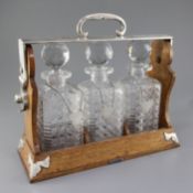 An early 20th century silver plate mounted oak Betjemann's Patent "The Tantalus" with three cut