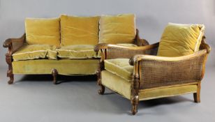 An early 20th century foliate carved walnut three piece bergere suite, with double caning and gold