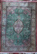 An Isphahan style silk rug, with central foliate medallion in a field of scrolling foliage, on a