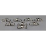 A set of eight Edwardian novelty silver menu holders modelled as fox masks on crossed riding