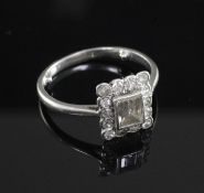 A mid 20th century platinum and diamond cluster ring, with central emerald cut stone bordered by