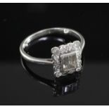 A mid 20th century platinum and diamond cluster ring, with central emerald cut stone bordered by