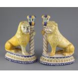 A pair of Italian maiolica 'lion' candlesticks, 19th century, each lion clasping a column, on an