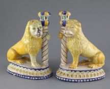 A pair of Italian maiolica 'lion' candlesticks, 19th century, each lion clasping a column, on an