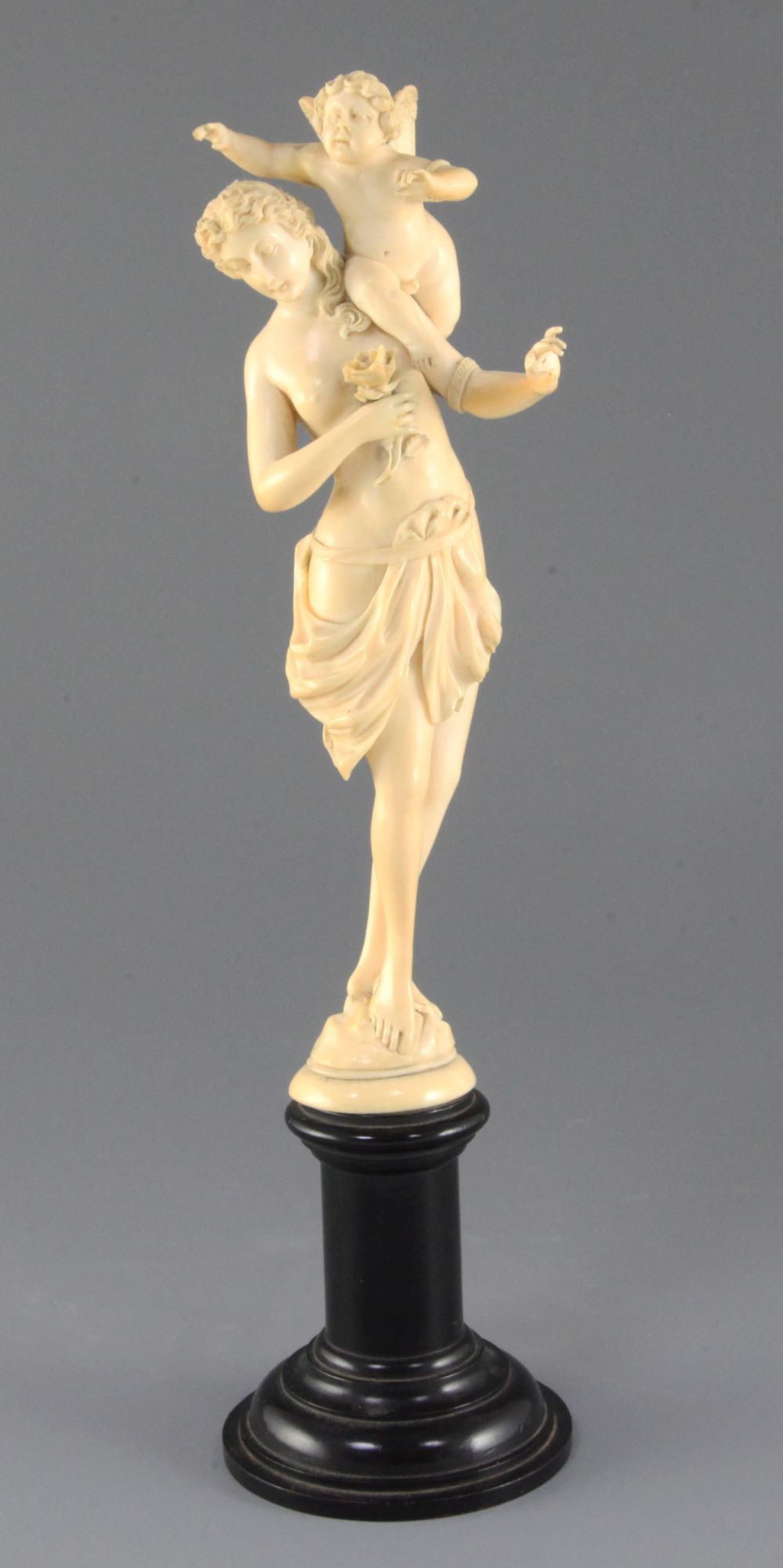 A 19th century French Dieppe ivory carving of Venus and Cupid, on an ebonised socle, Overall H.13.