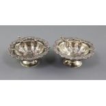 A pair of late 19th century Russian? silver circular salts with two spoons, with foliate rims, one