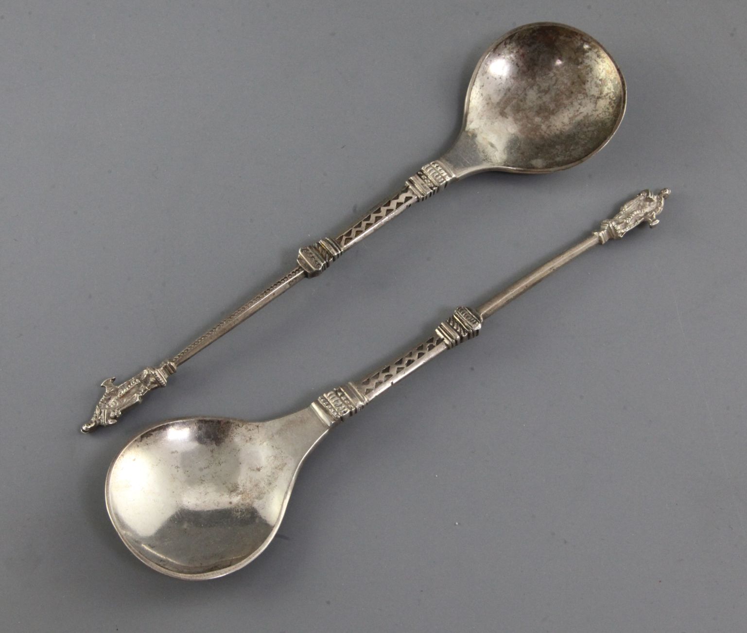 Two similar Scandinavian white metal spoons, with stepped and panelled stems and figural