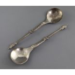 Two similar Scandinavian white metal spoons, with stepped and panelled stems and figural