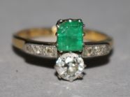 An 18ct gold and platinum, emerald and diamond crossover ring, with diamond set shoulders, size J.