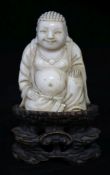 A Chinese ivory seated figure of Buddha, on a wood stand, 9cm