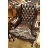 A beech frame wing back easy chair, upholstered in studded hide