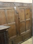 A 17th century oak carved and panelled two door hanging cupboard, W.150cm (a.f.)